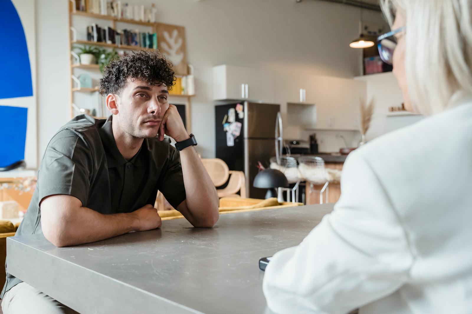 A man across a cafe table looking bored while someone talks at him