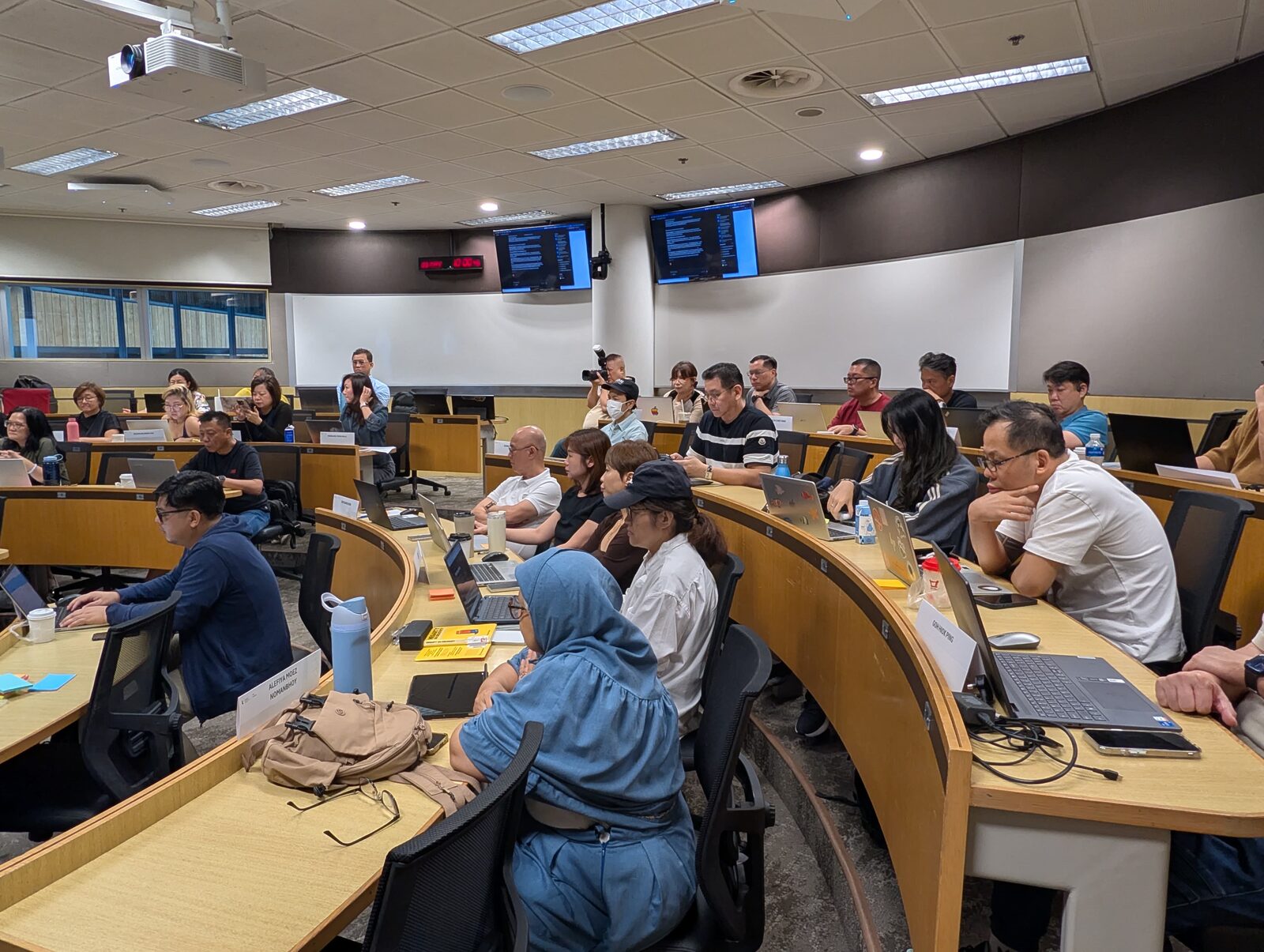 The SMU Academy Intake 5 cohort heads-down on their laptops, building AI projects together on the final day