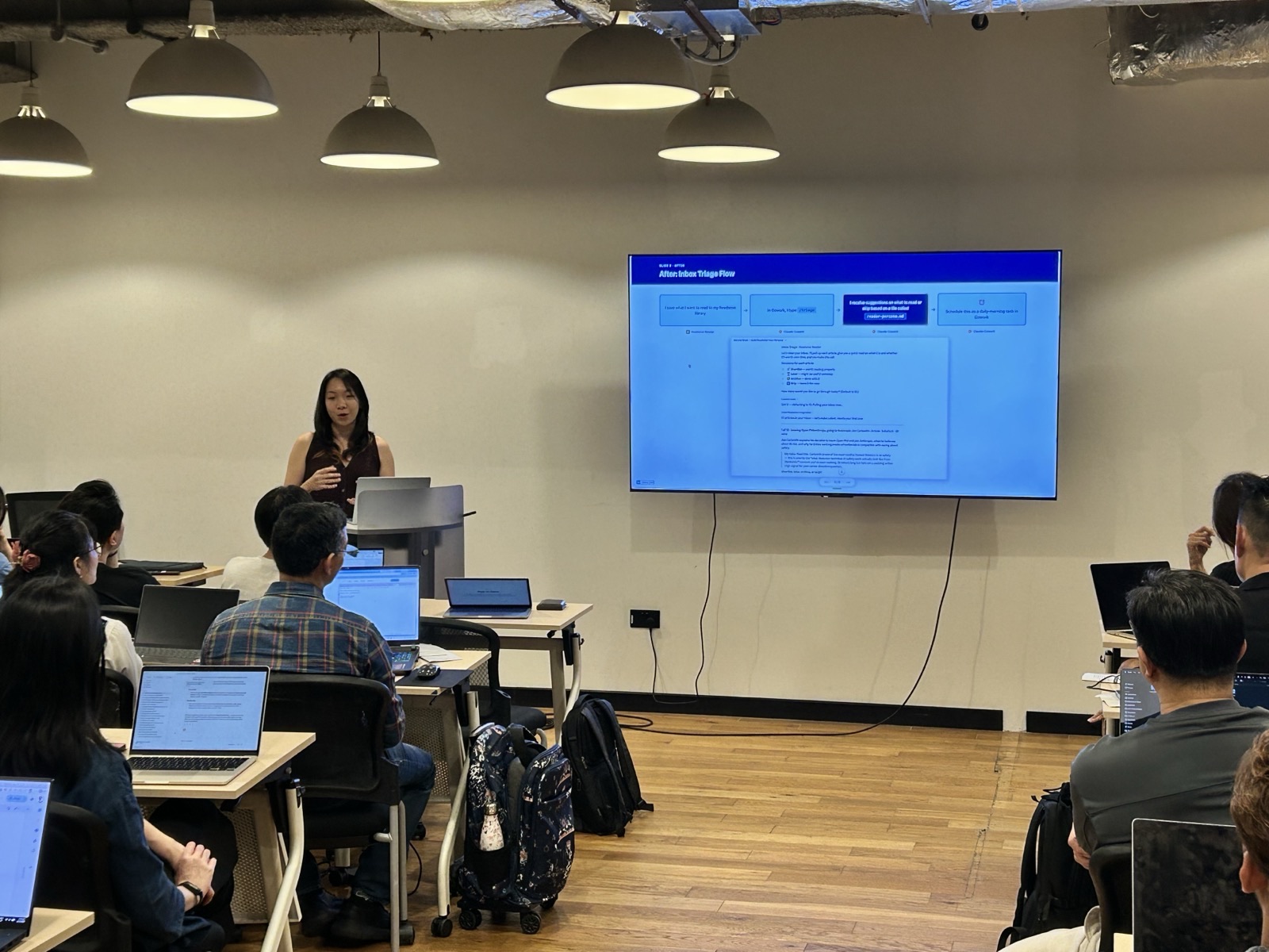 A speaker presenting to a full room of attendees at an AI Power Users meetup in Singapore