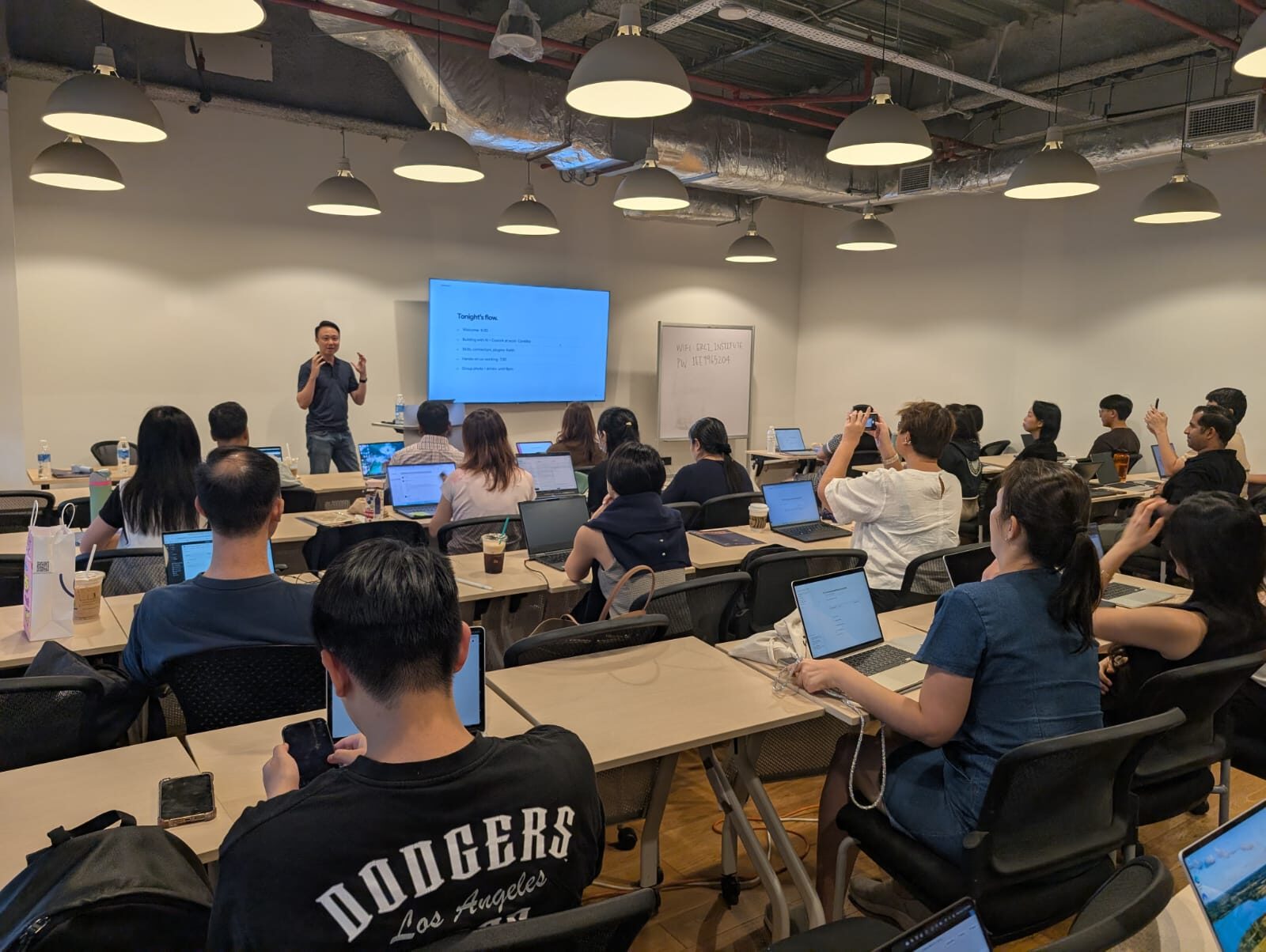 Keith Teo presenting tonight's run of show to a full room of attendees with laptops at the AI Power Users Meetup 02 in Singapore